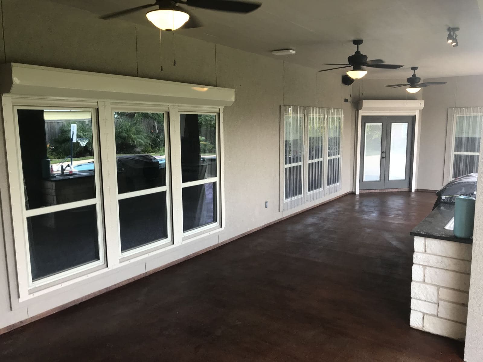 Covered back patio with a dark acid-stained concrete floor and ceiling fans