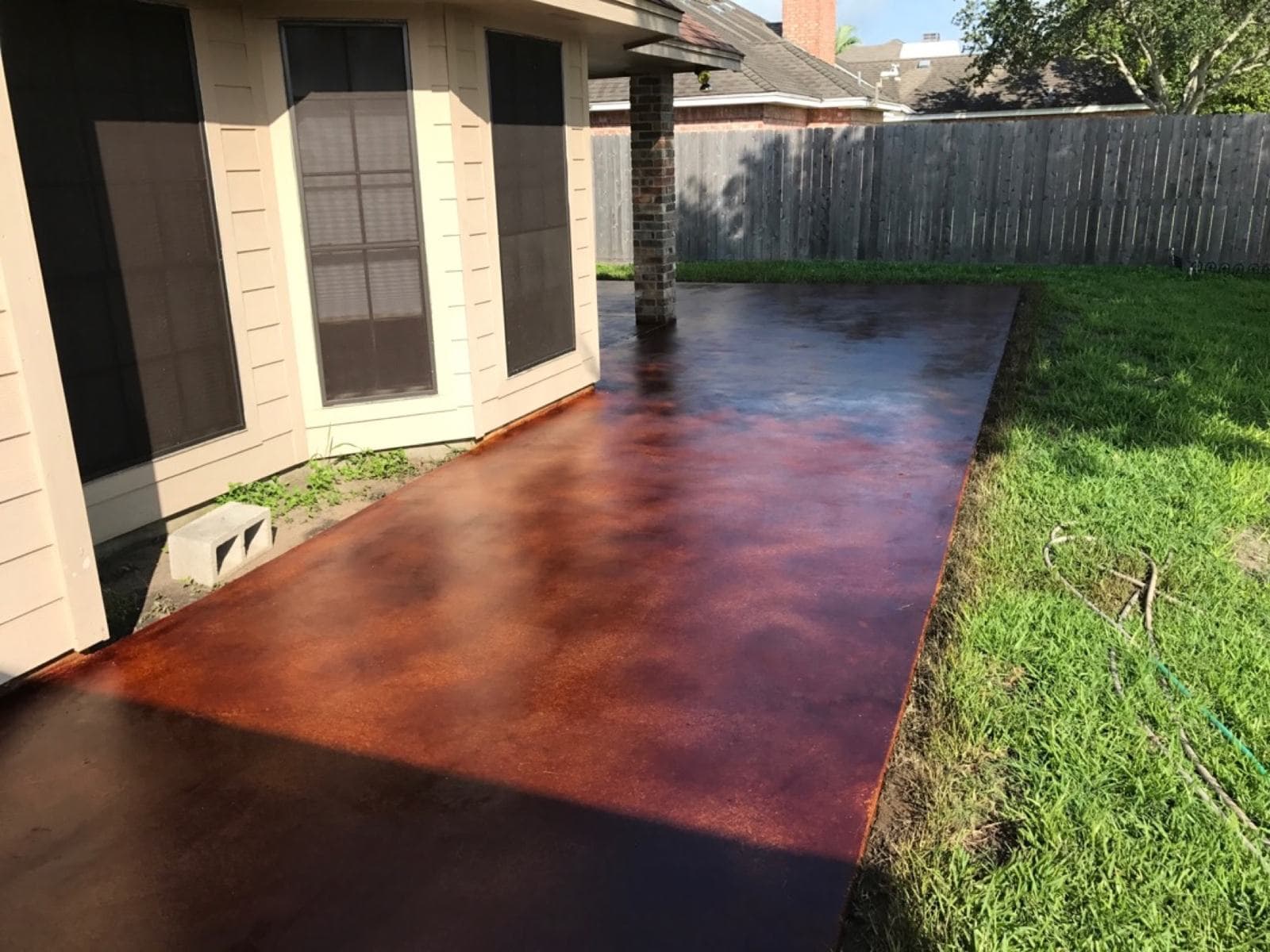 Deep mahogany acid-stained concrete patio running the length of a home
