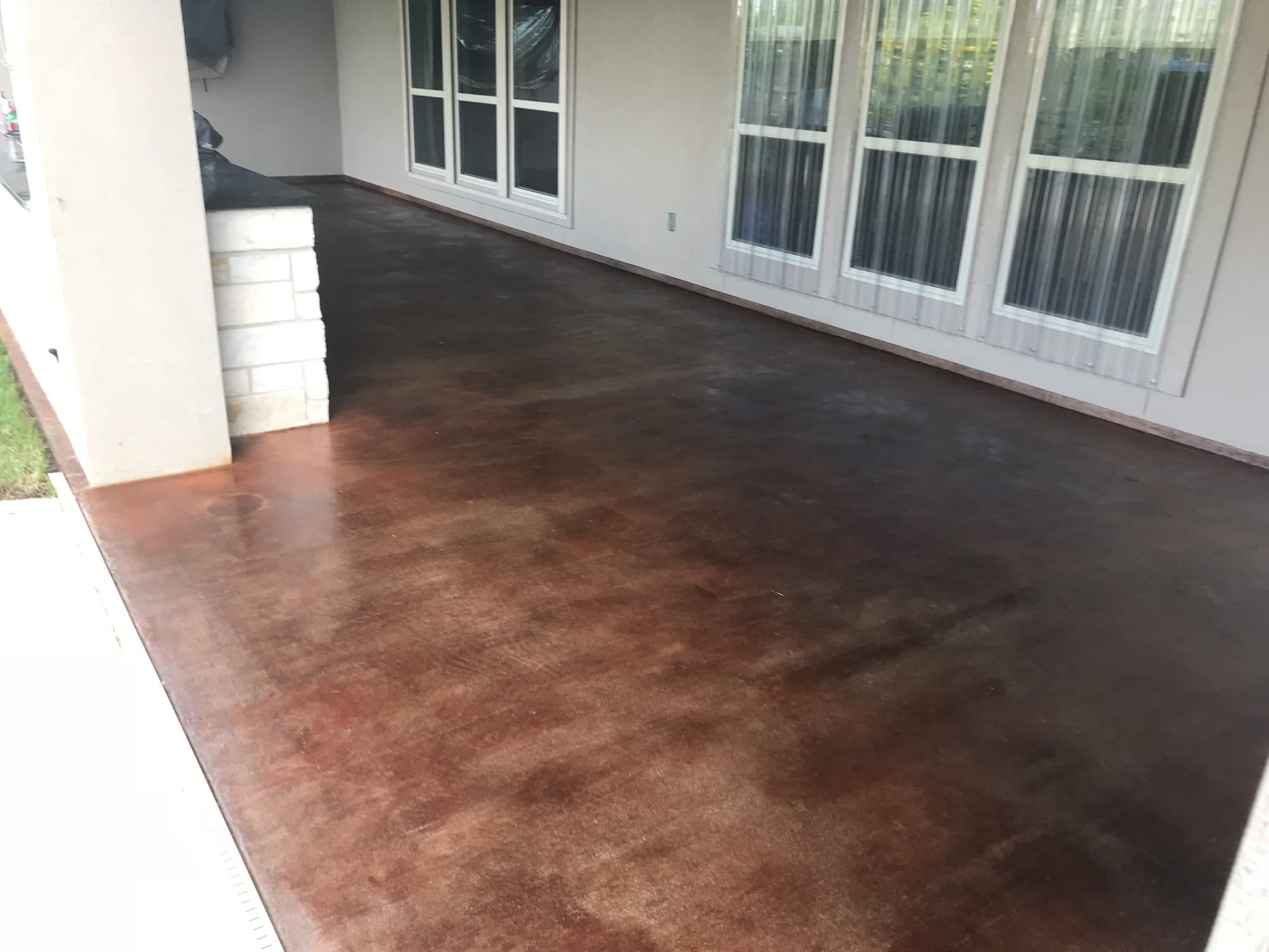 Deep mahogany acid-stained patio running along the side of a home