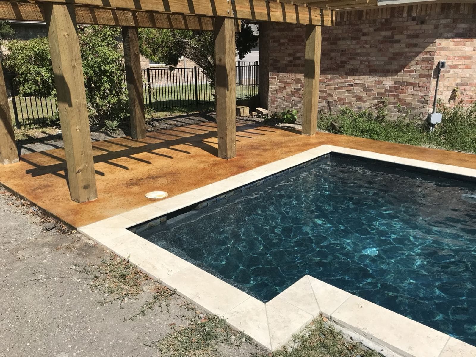Stained pool deck with a cedar pergola