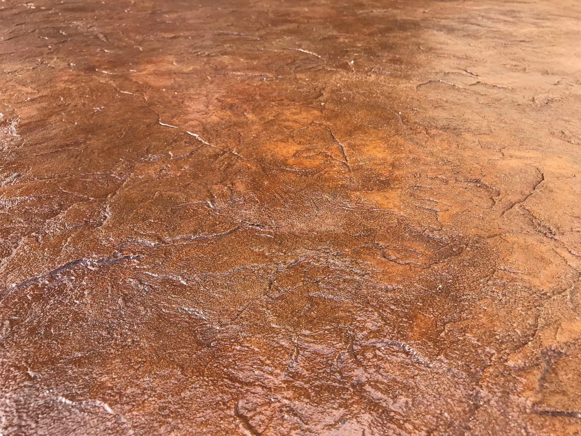 Close-up of rust-orange acid-stained concrete with mottled marbling