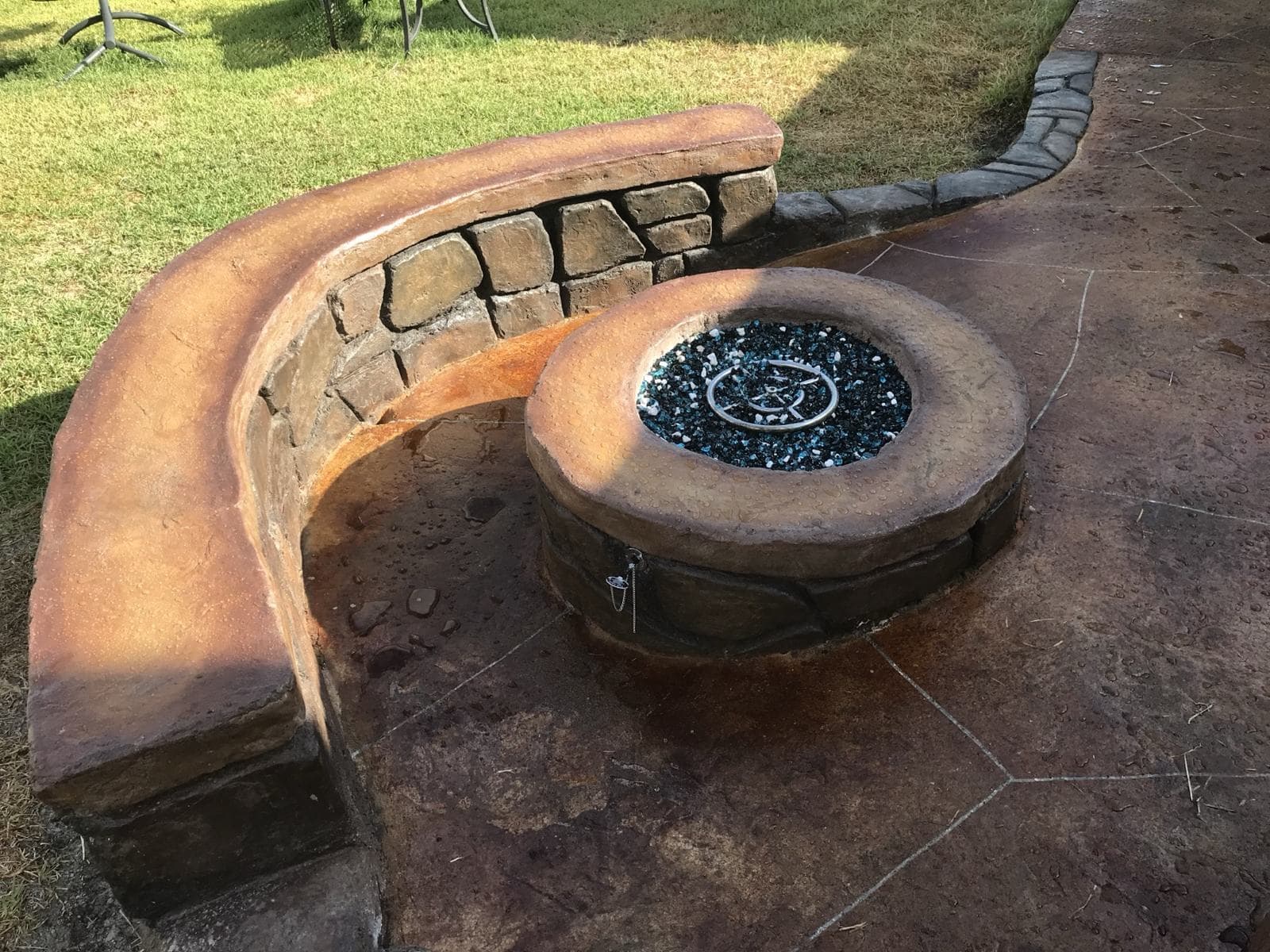 Concrete fire pit with a curved stamped seat wall around it