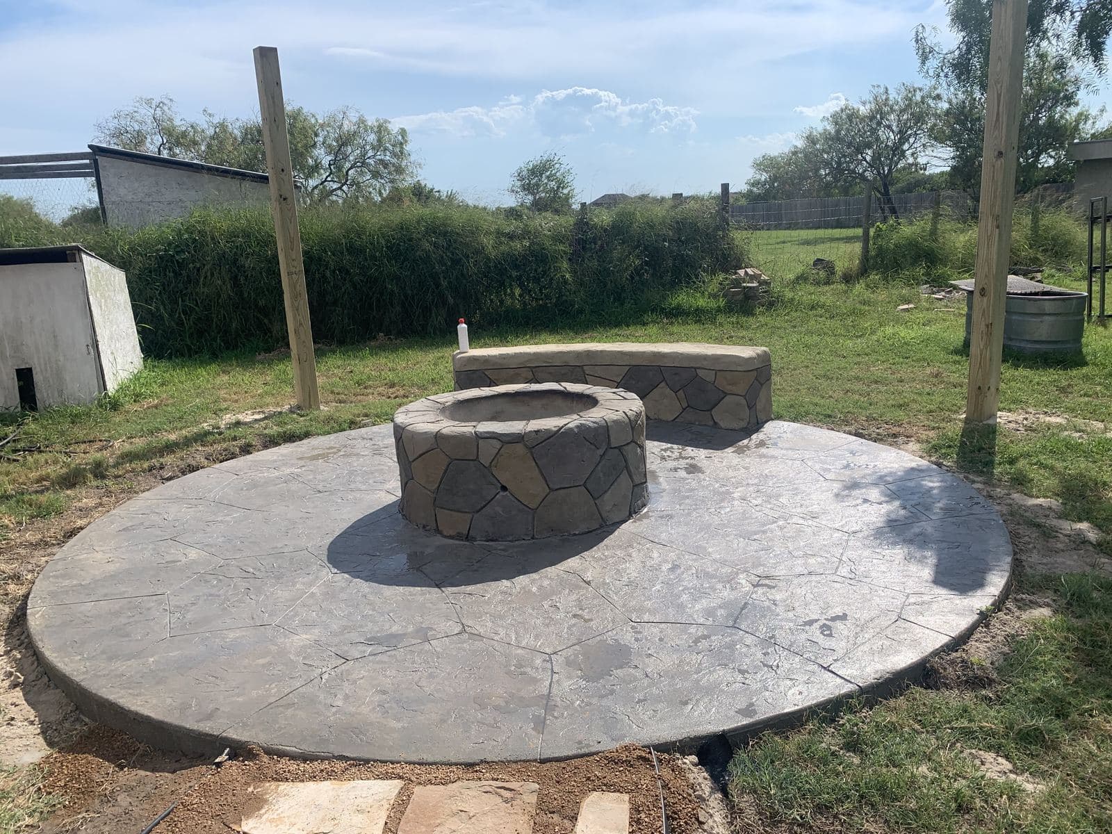 Stone fire pit and matching bench on a round stamped slab