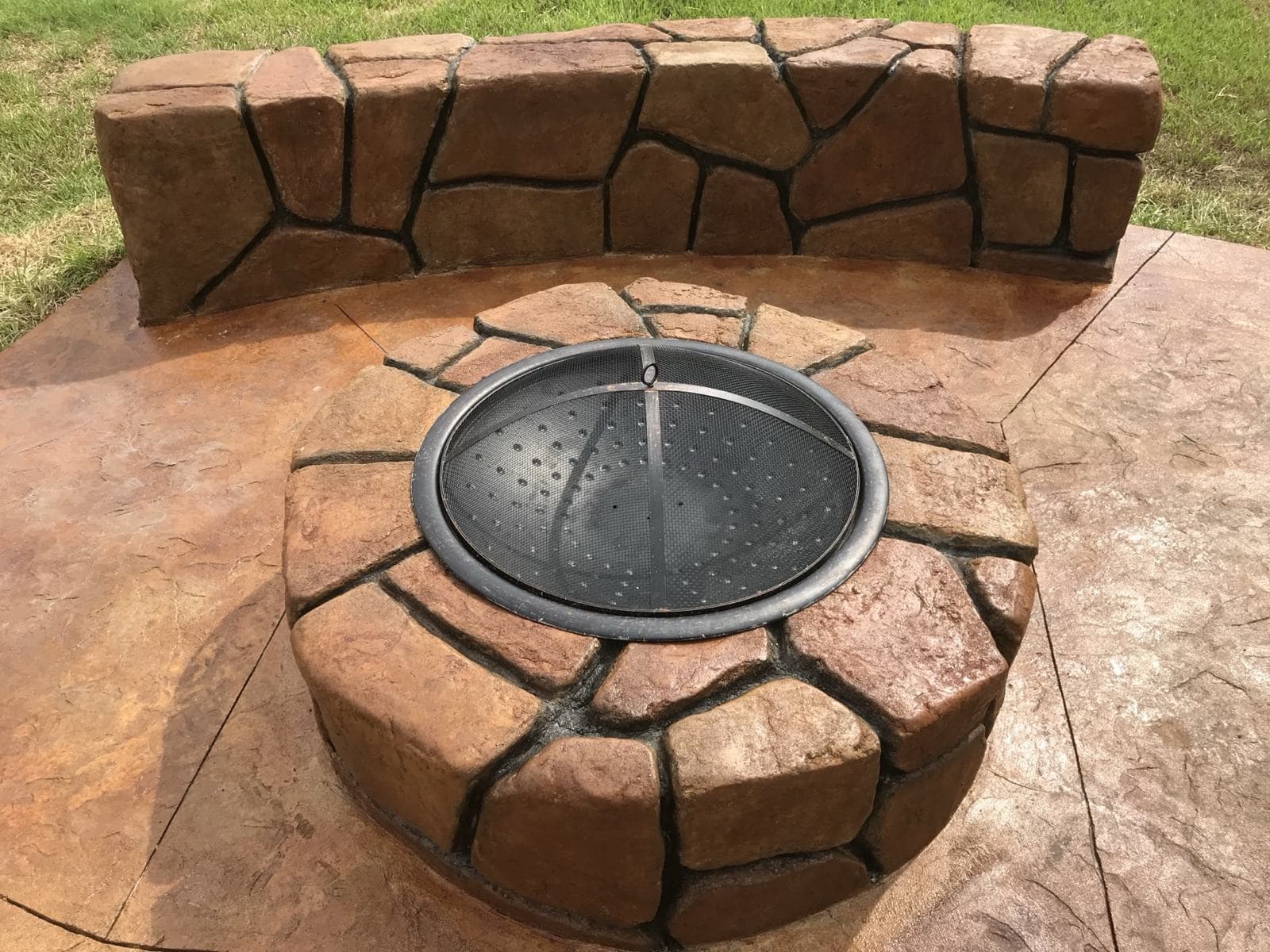 Round stone-look concrete fire pit on a finished patio