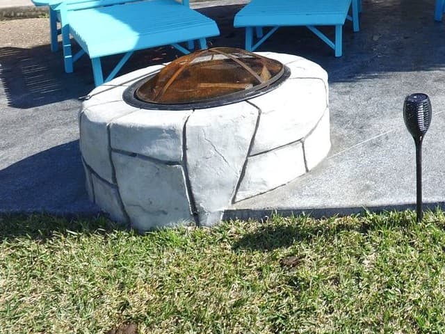 Stone-look fire pit on a gray stamped concrete patio
