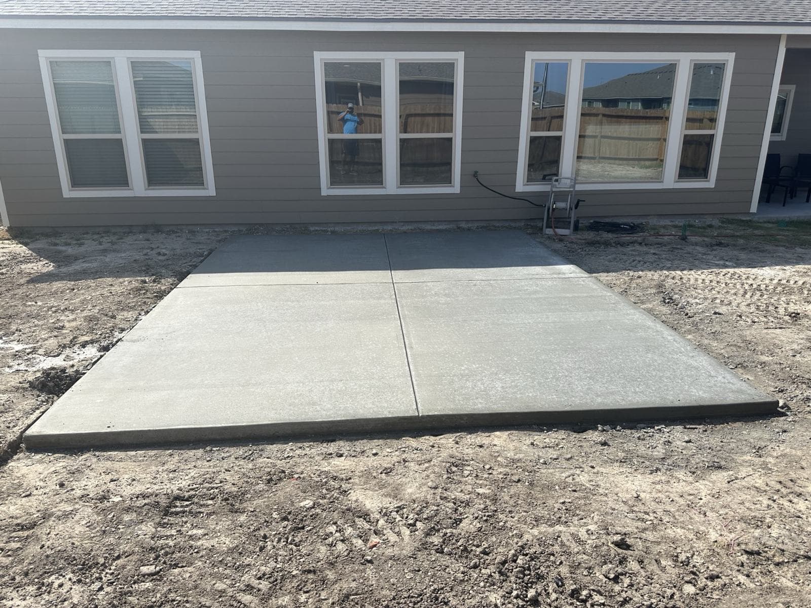 Freshly poured and finished concrete slab behind a home