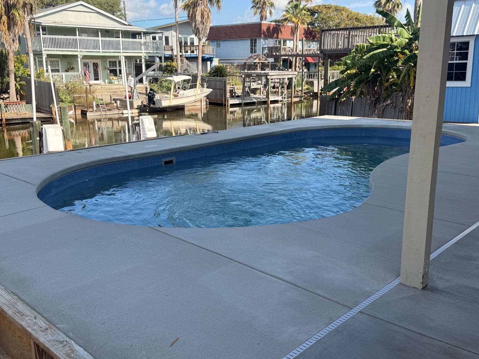 Fiberglass pool with a broom-finish deck overlooking a canal