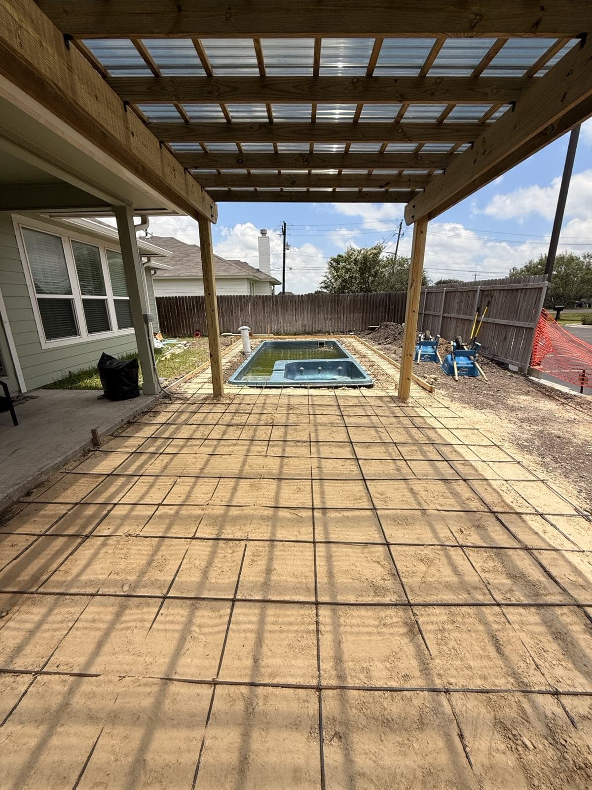 Fiberglass pool beside a covered patio with a finished deck
