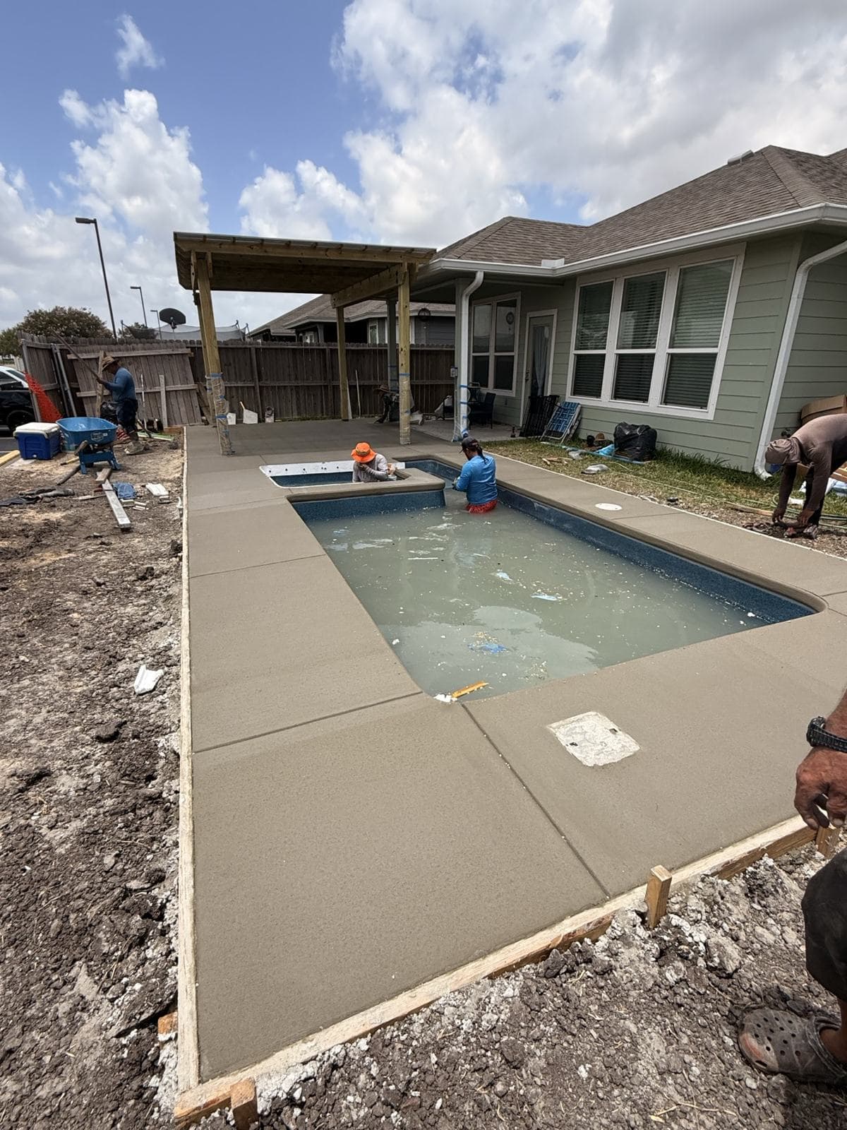 Crew pouring a concrete deck around a newly installed fiberglass pool