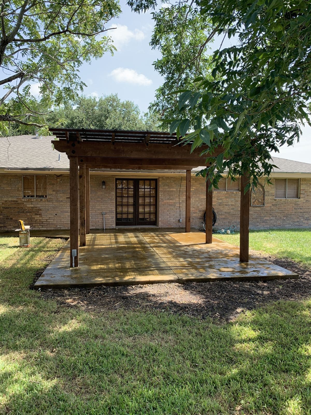 Cedar pergola over a new concrete slab under shade trees