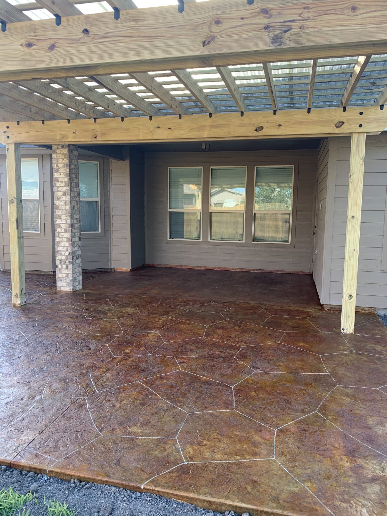 Pergola over a flagstone-stamped patio at a covered entry