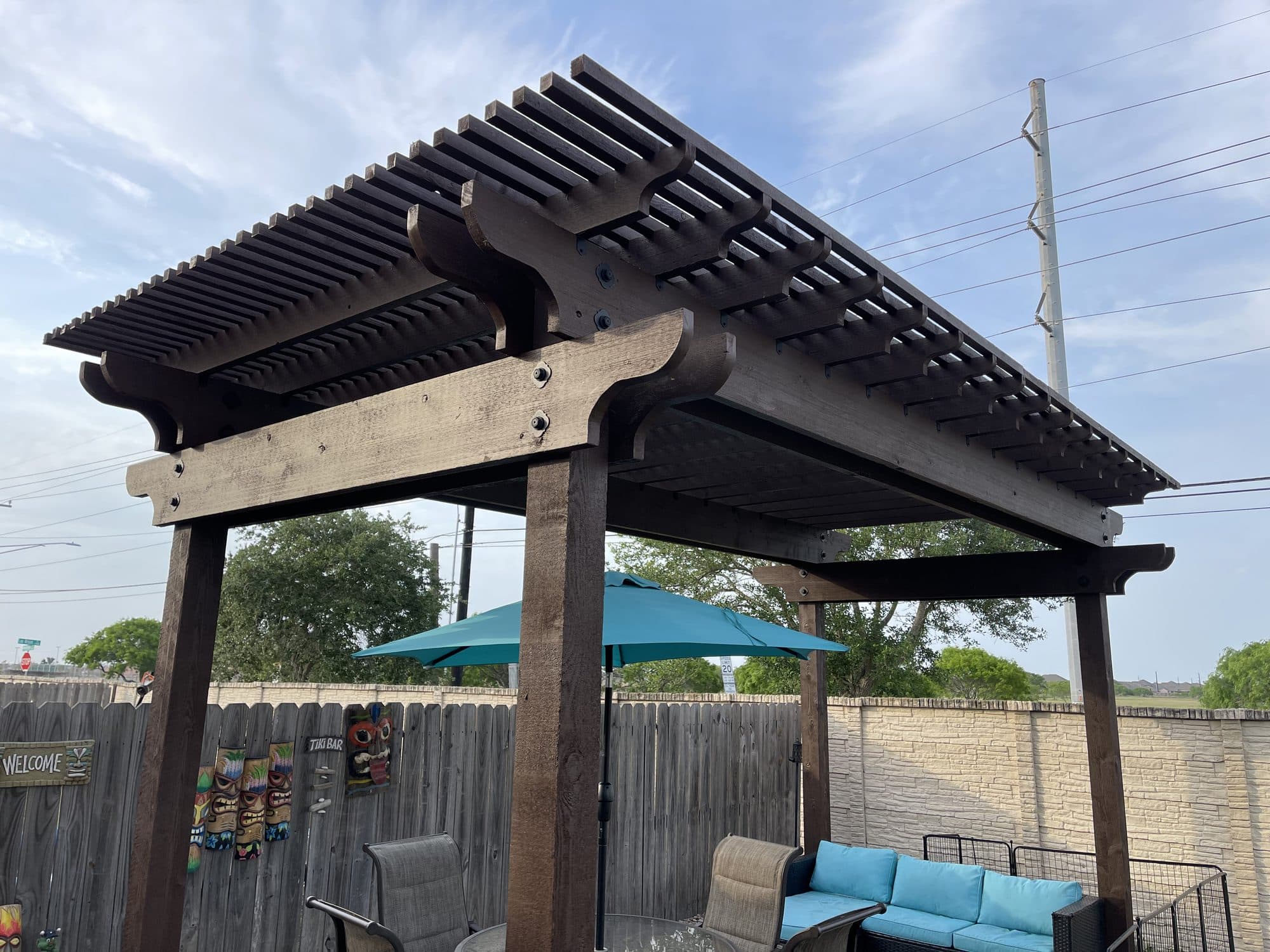 Dark-stained pergola over a patio with teal outdoor seating