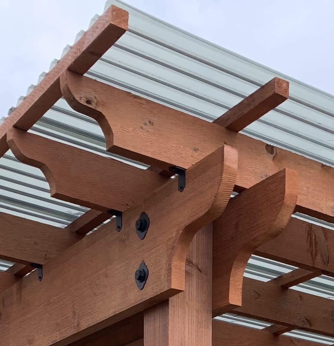 Close-up of cedar pergola rafters and corbels under a polycarbonate roof