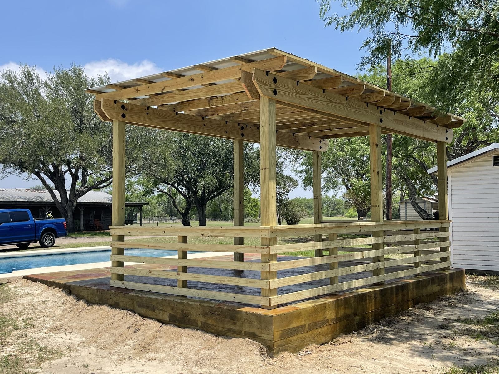 New pergola with horizontal wood railings on a raised slab
