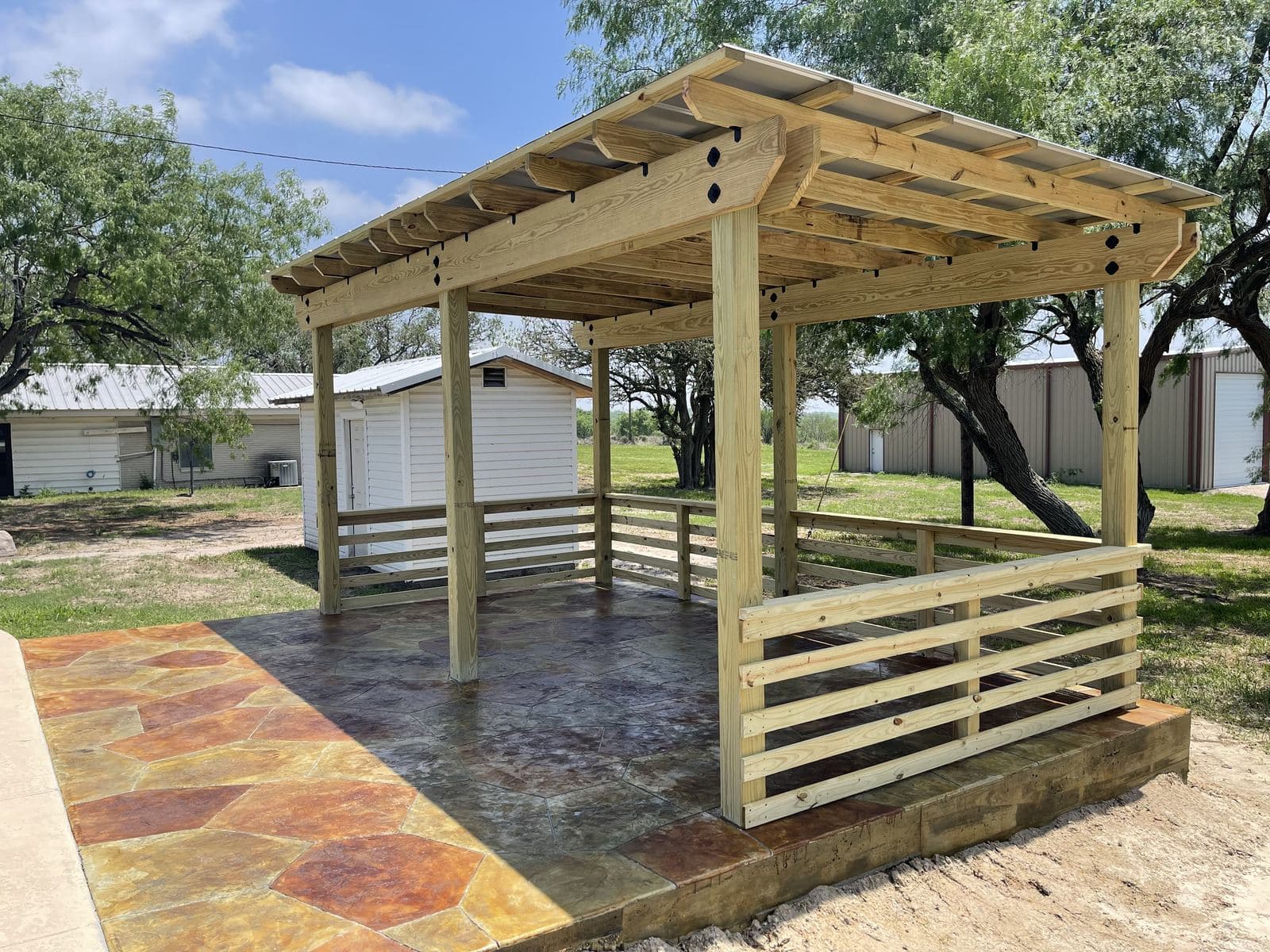 Pergola with wood railings over a stained stamped flagstone patio