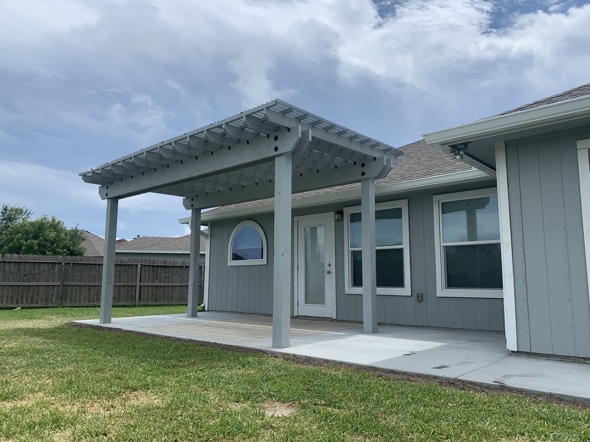 White pergola attached to a gray-blue home