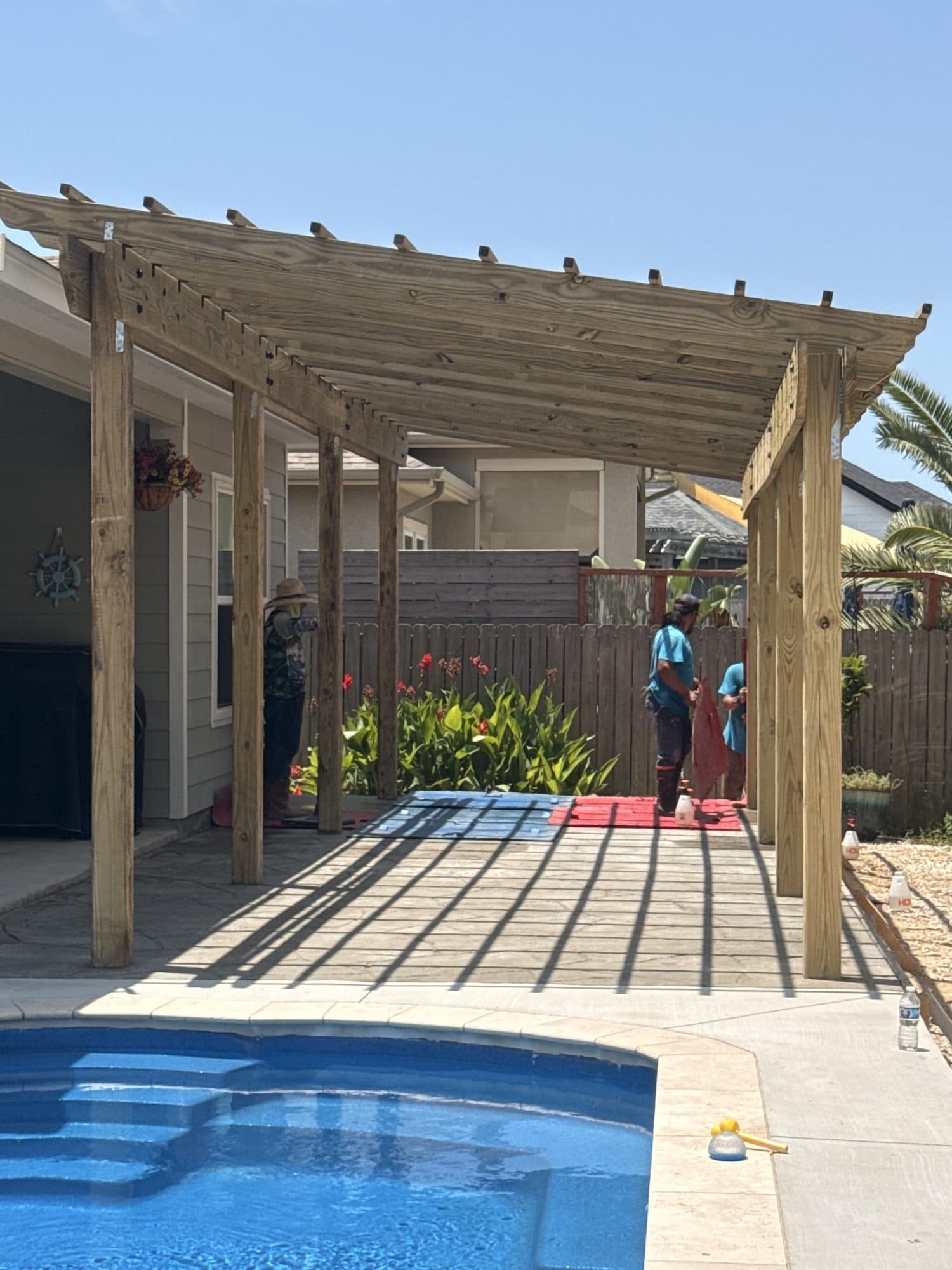 Cedar pergola beside a pool with a stamped concrete deck
