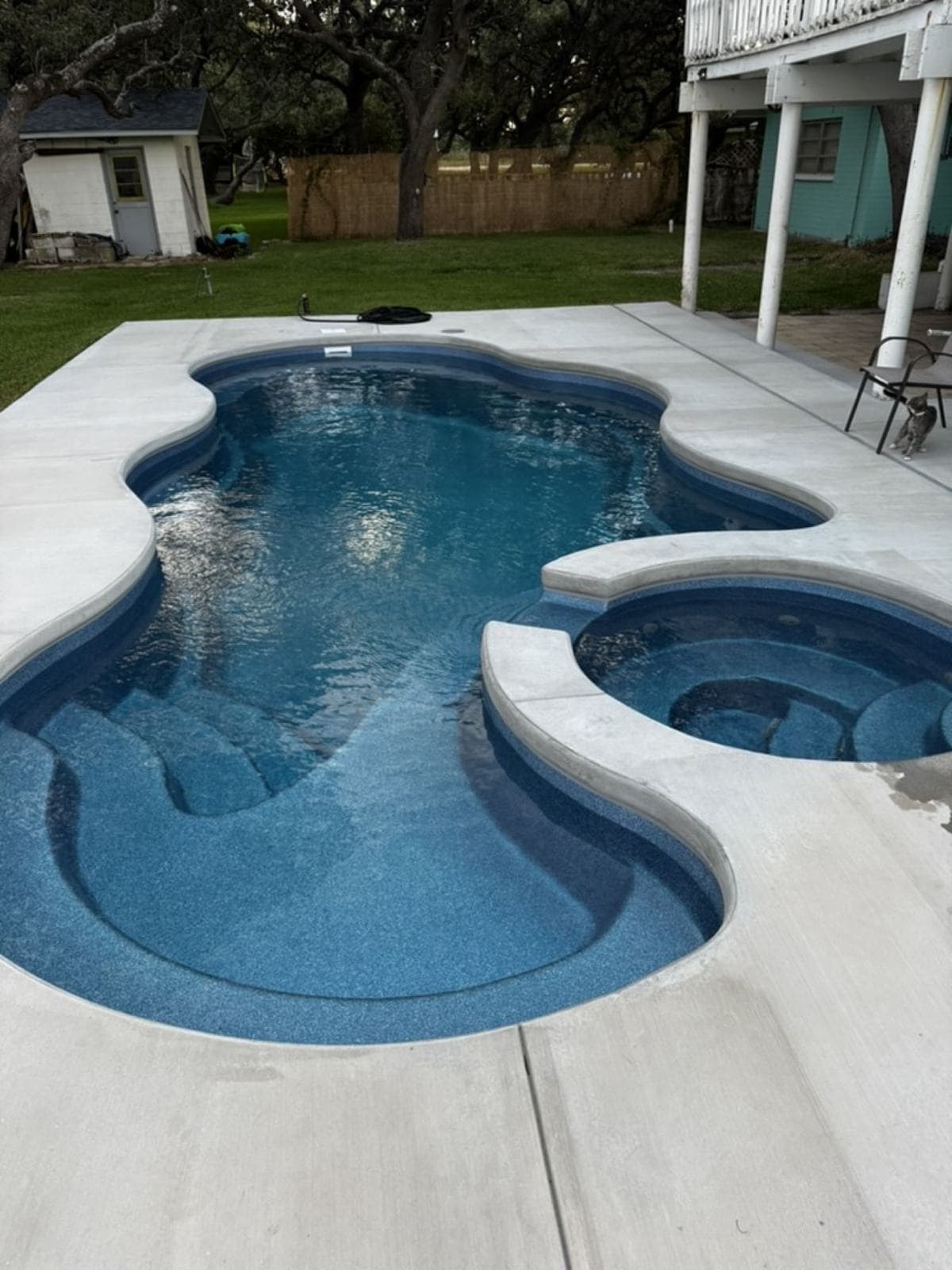 Fiberglass pool with a raised spa and a clean concrete deck