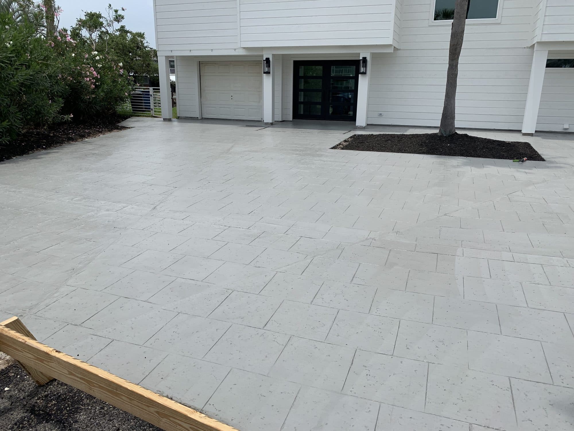 Light-gray ashlar-pattern stamped driveway at a two-story white home
