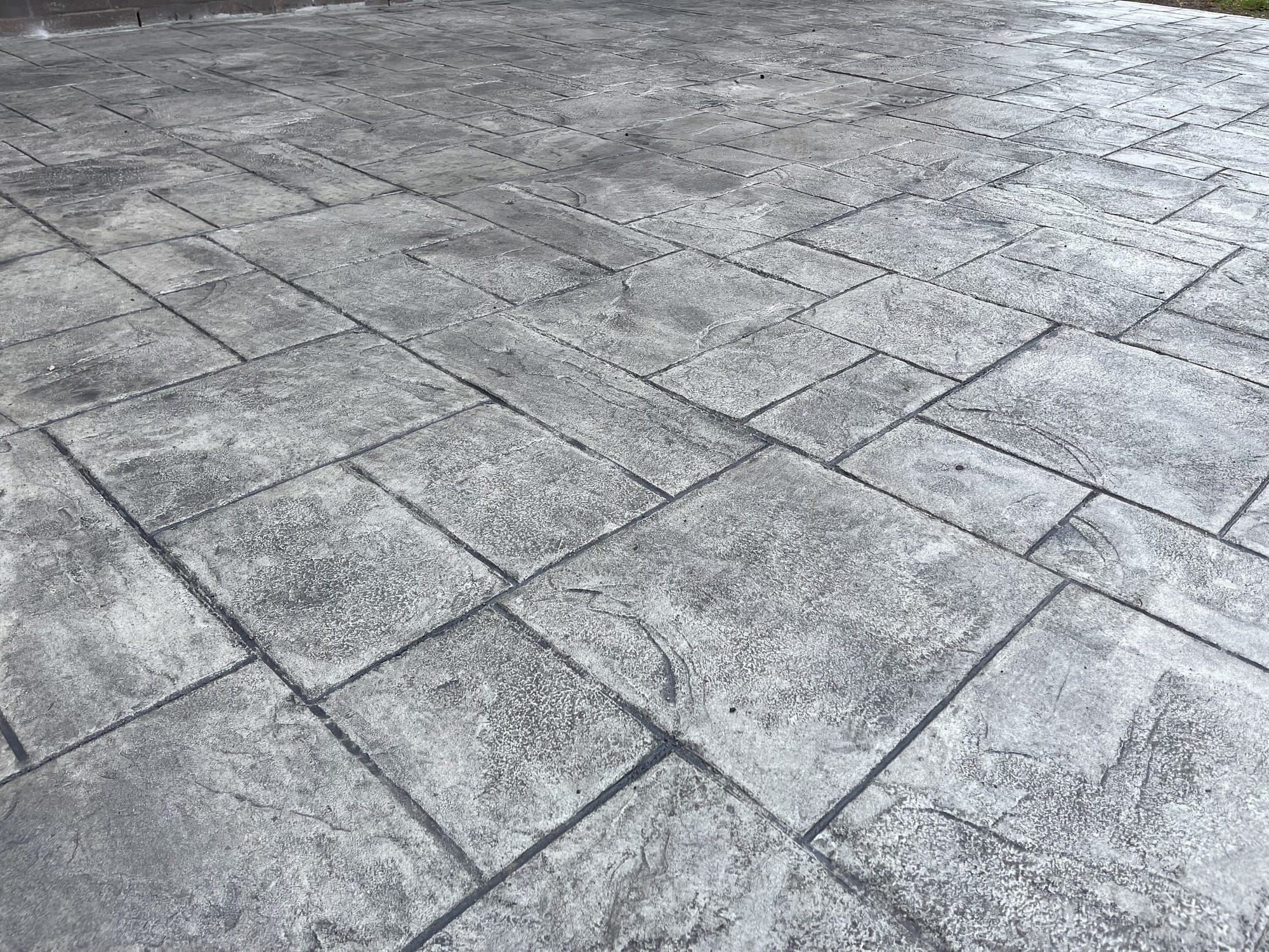 Close-up of gray ashlar-pattern stamped concrete showing the stone texture