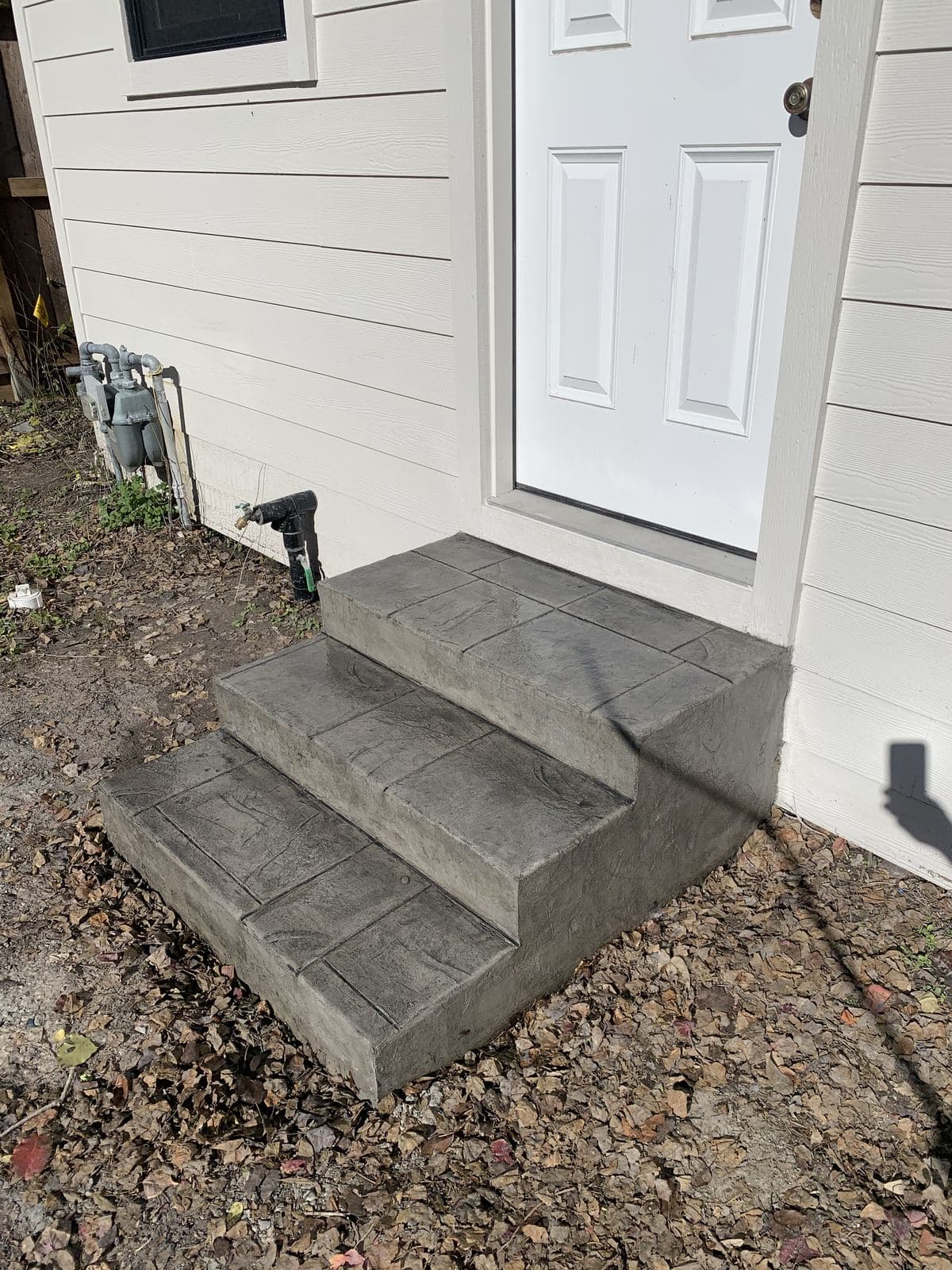 Gray stamped concrete steps leading up to a side door
