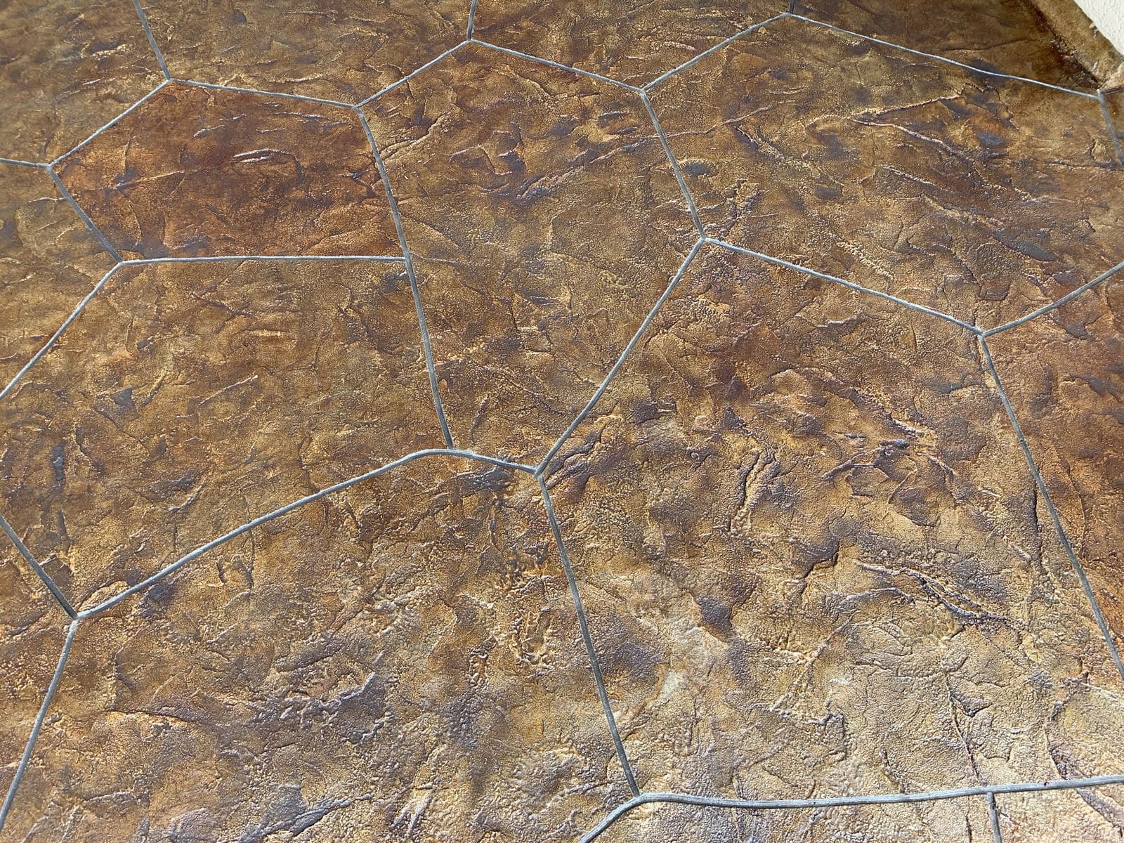 Close-up of stained flagstone-pattern stamped concrete in browns and golds